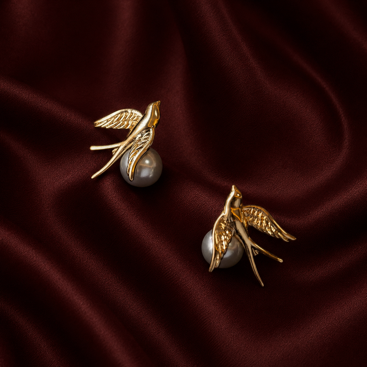 Finer gold bird and pearl earrings on burgundy silk